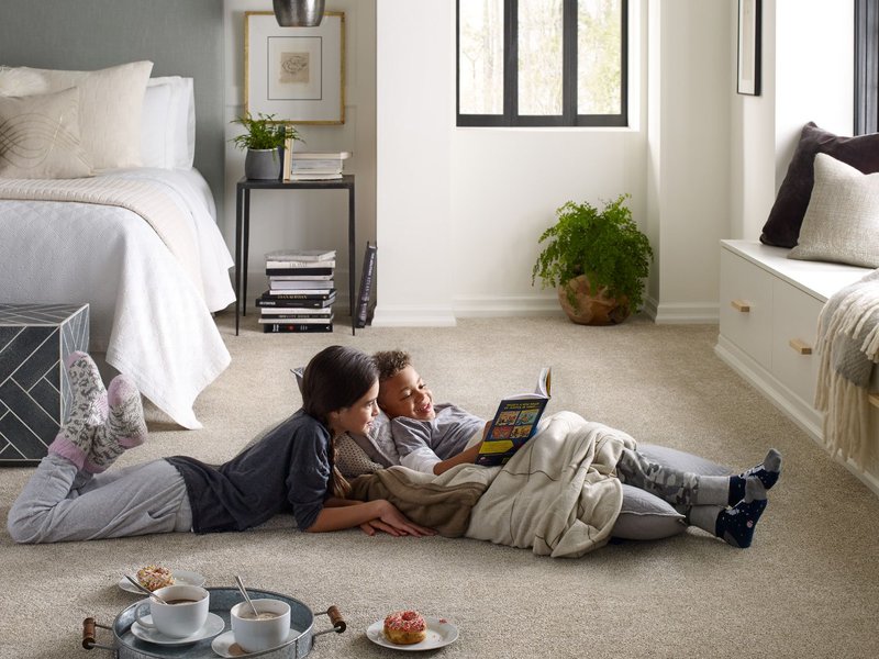 young boy and girl laying on carpet in bedroom reading a book