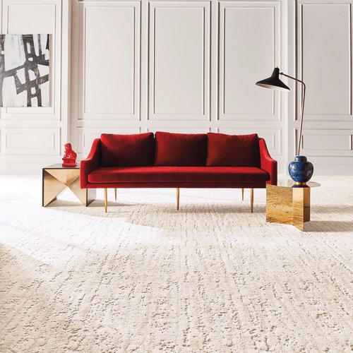 Bright living room with a red velvet couch and textured beige carpet throughout from Carpet Innovations in Denver, CO